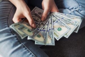 Stack of $100 bills a coach received from financing their online coaching program.